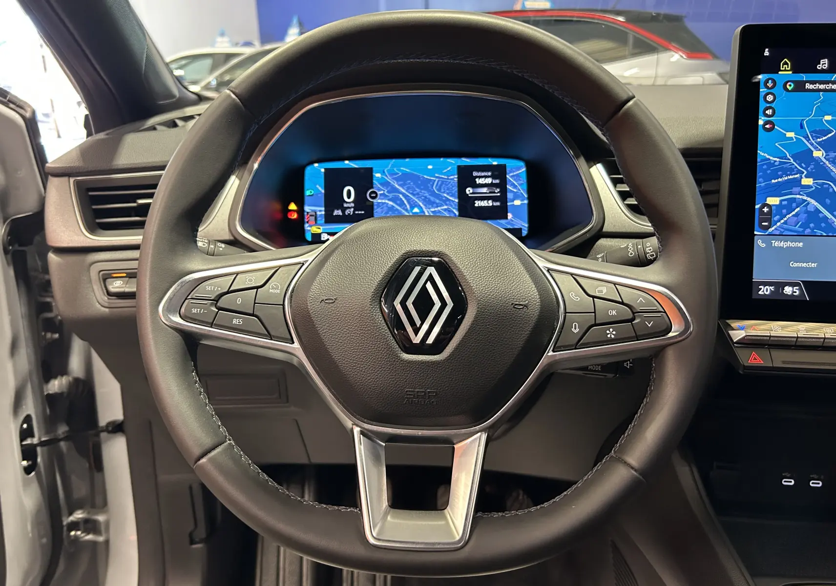 Vue centrée sur le volant noir du Renault Captur gris Rafale avec tableau de bord numérique et écran tactile GPS.