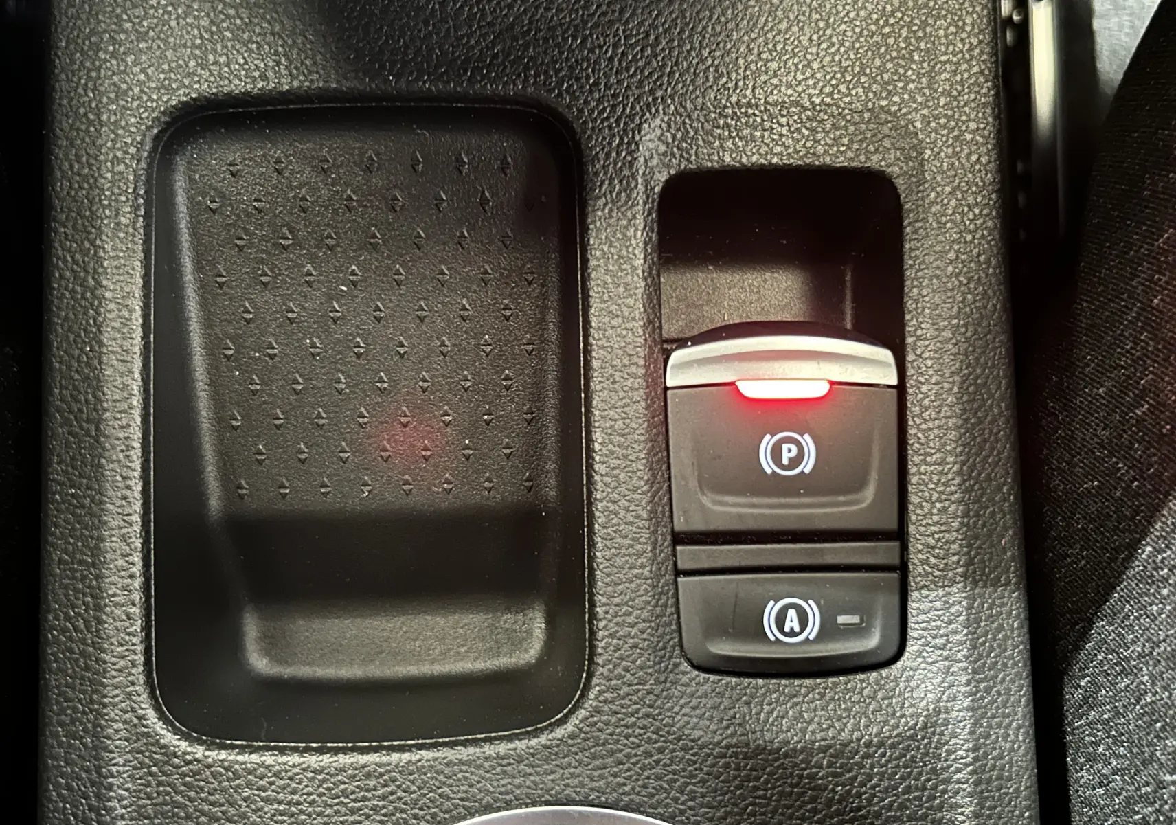 Gros plan sur la console centrale du Renault Captur gris Rafale, montrant le frein à main électronique avec témoin rouge allumé.