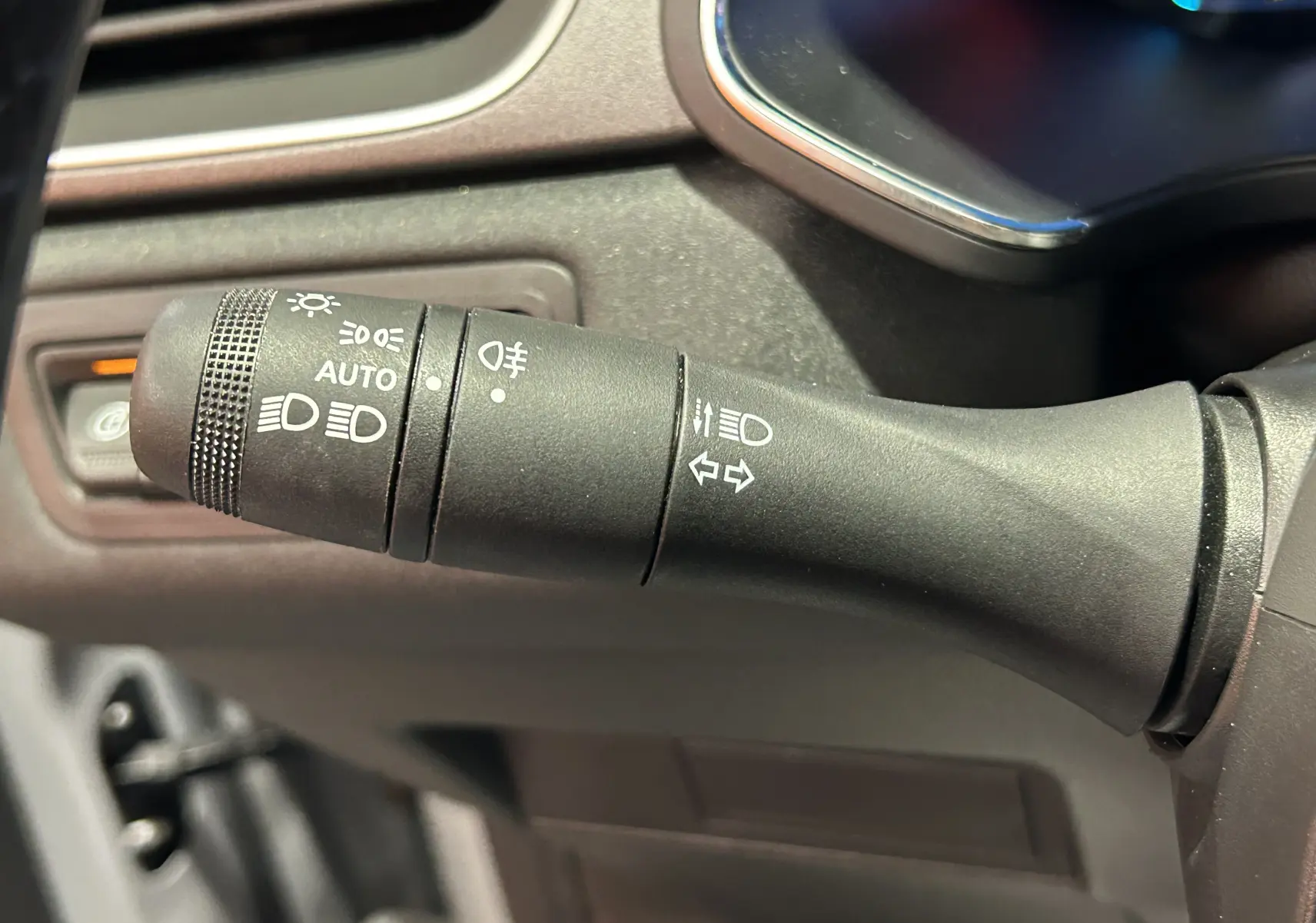 Gros plan sur la commande des feux et clignotants du tableau de bord d’un Renault Captur gris Rafale 2025.