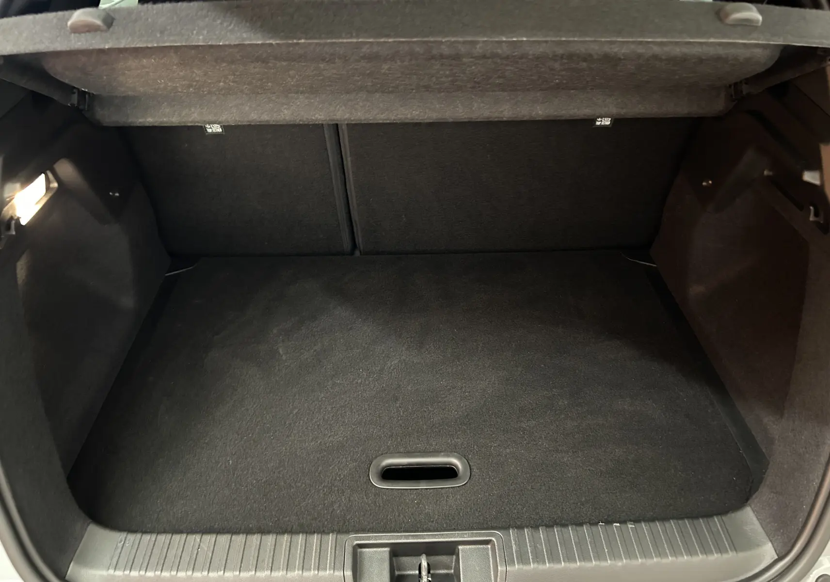 Coffre ouvert vu de face du Renault Captur gris Rafale, montrant un espace de rangement propre et bien fini.