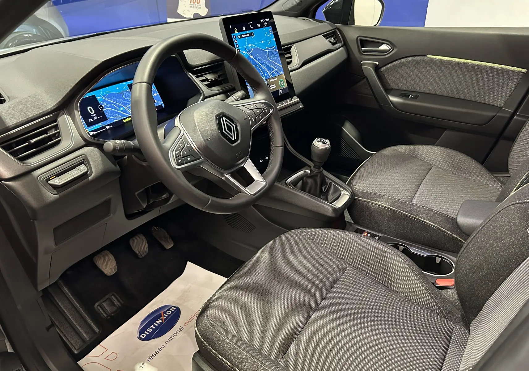 Vue intérieure côté conducteur du Renault Captur gris Rafale 2025, avec tableau de bord digital et boîte manuelle.