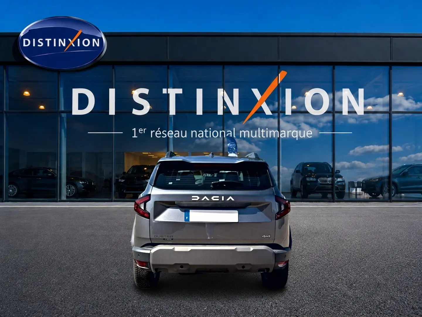 Vue arrière d'un Dacia Duster gris schiste 2026 garé devant une vitrine avec logo Distinxion.