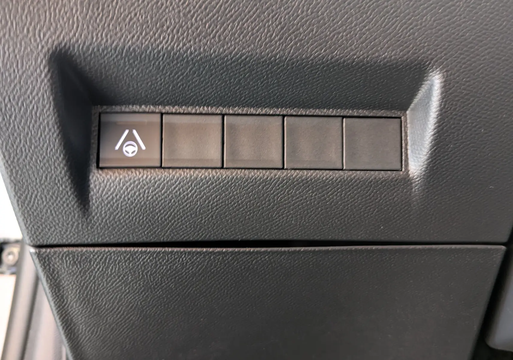 Gros plan sur le bouton d'assistance au maintien de voie dans l'habitacle noir d'une Peugeot 208 Hybrid 145ch GT 2024.