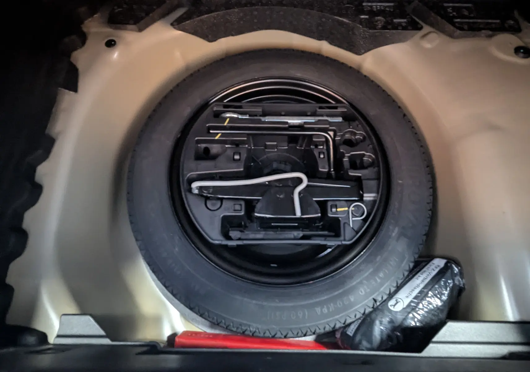 Roue de secours et kit de réparation logés dans le coffre d'une Peugeot 208 Hybrid 145ch gris Artens 2024.