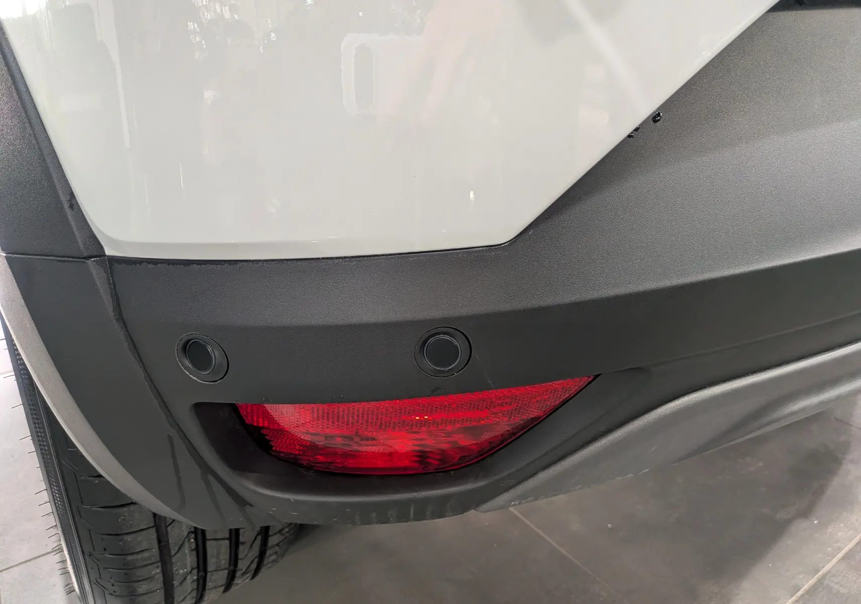 Gros plan sur le feu arrière droit rouge et le pare-chocs noir du Dacia Sandero Stepway blanc glacier 2025.