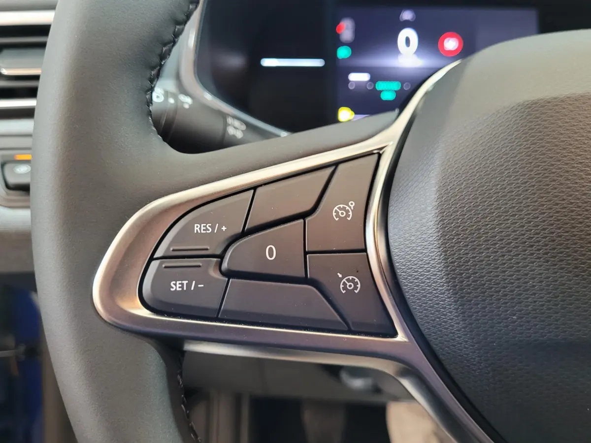 Gros plan sur les commandes du régulateur de vitesse à gauche du volant cuir de la Renault Clio bleu 2025.