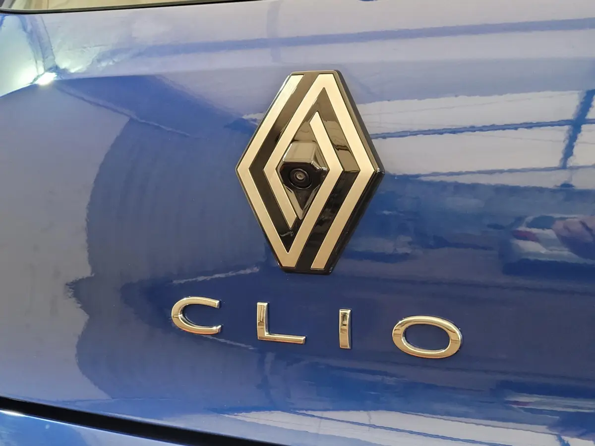 Gros plan sur le logo Renault et l'inscription Clio sur la malle arrière d'une Renault Clio bleue brillante.