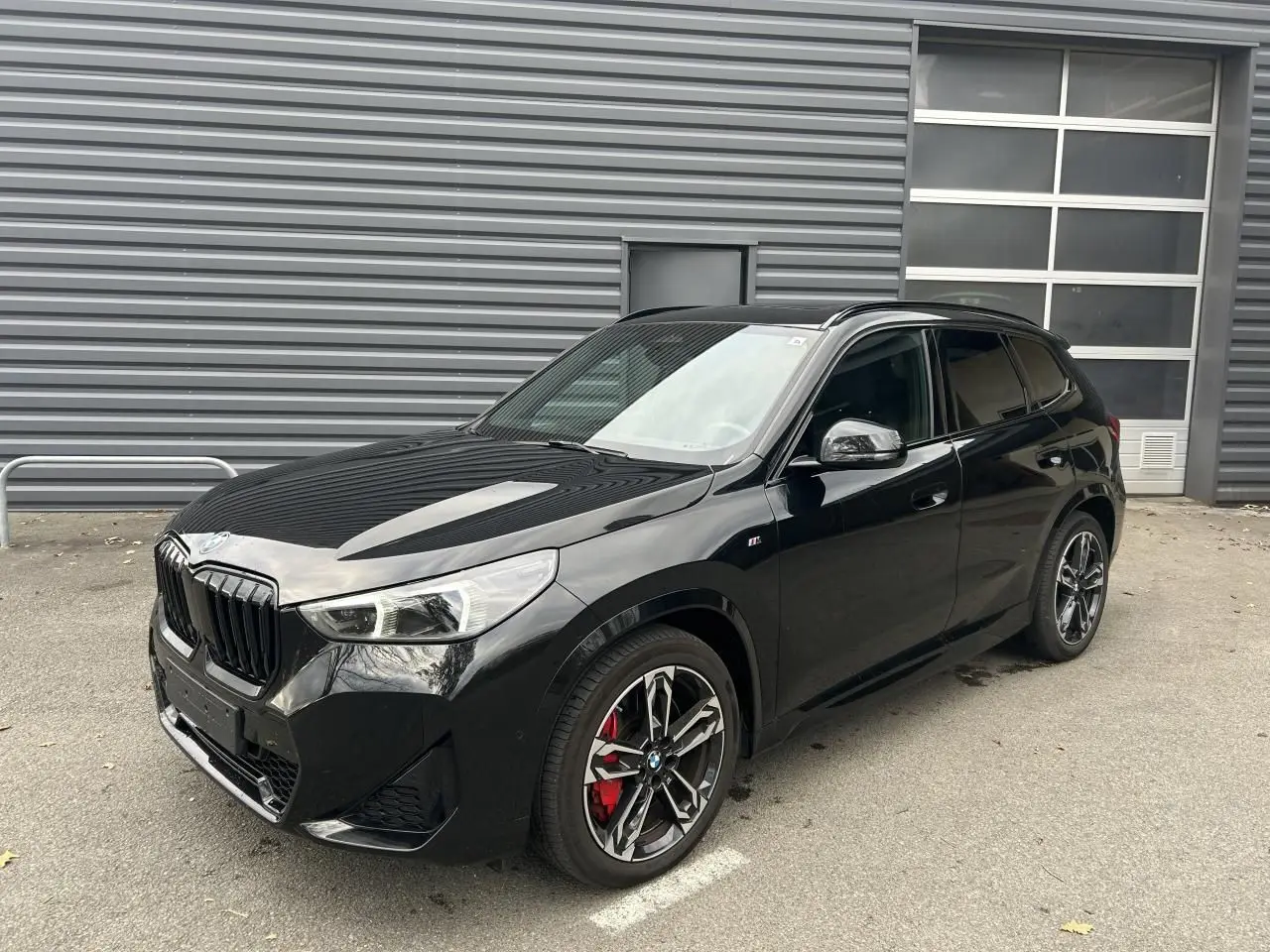 BMW X1 XDRIVE 20D M SPORT noir Black Saphire vue 3/4 avant avec jantes sport et étriers rouges visibles