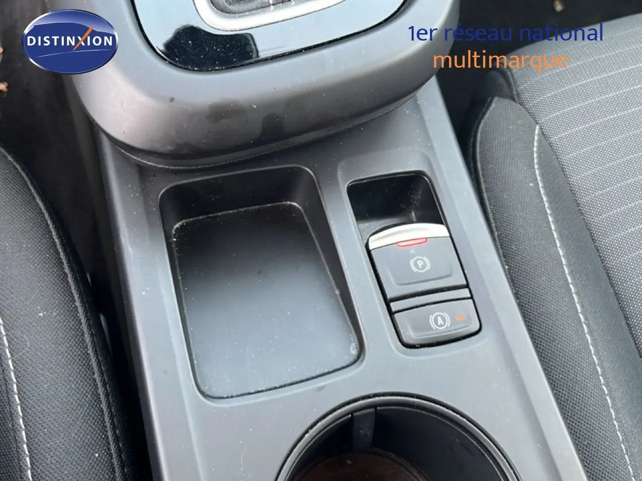 Gros plan sur la console centrale noire avec boutons de frein à main et arrêt moteur de la Renault Arkana 2025.