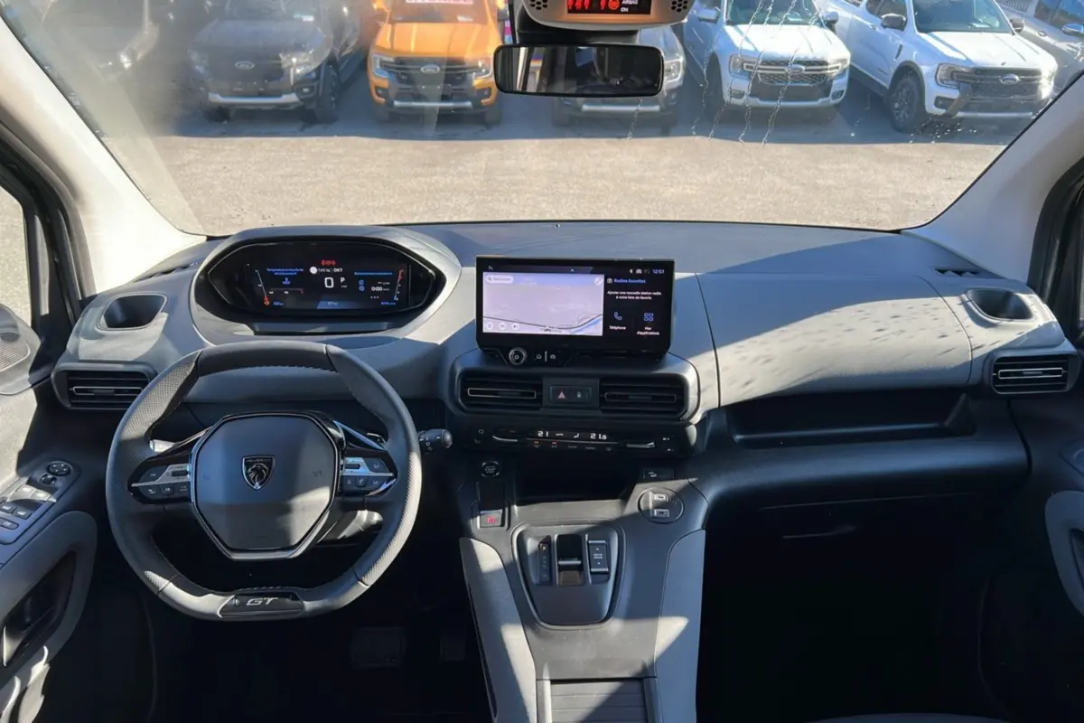 Vue intérieure avant du Peugeot Rifter 2025 GT Plus, tableau de bord moderne avec écran tactile et volant cuir multifonctions.