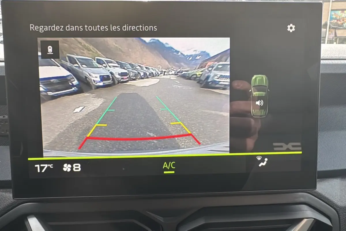 Écran multimédia du Dacia Duster 2025 montrant la caméra de recul avec guidage coloré et vue arrière du véhicule.
