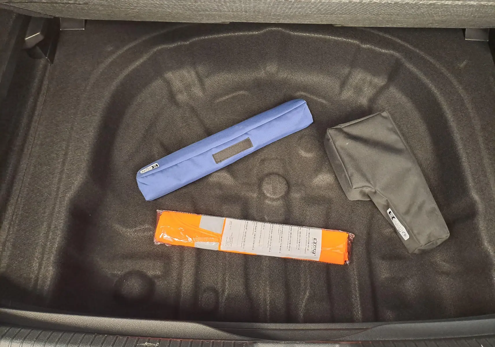 Coffre ouvert vu de dessus d'une Volkswagen Golf 2024, version Bleu Anémone, avec accessoires de sécurité posés.
