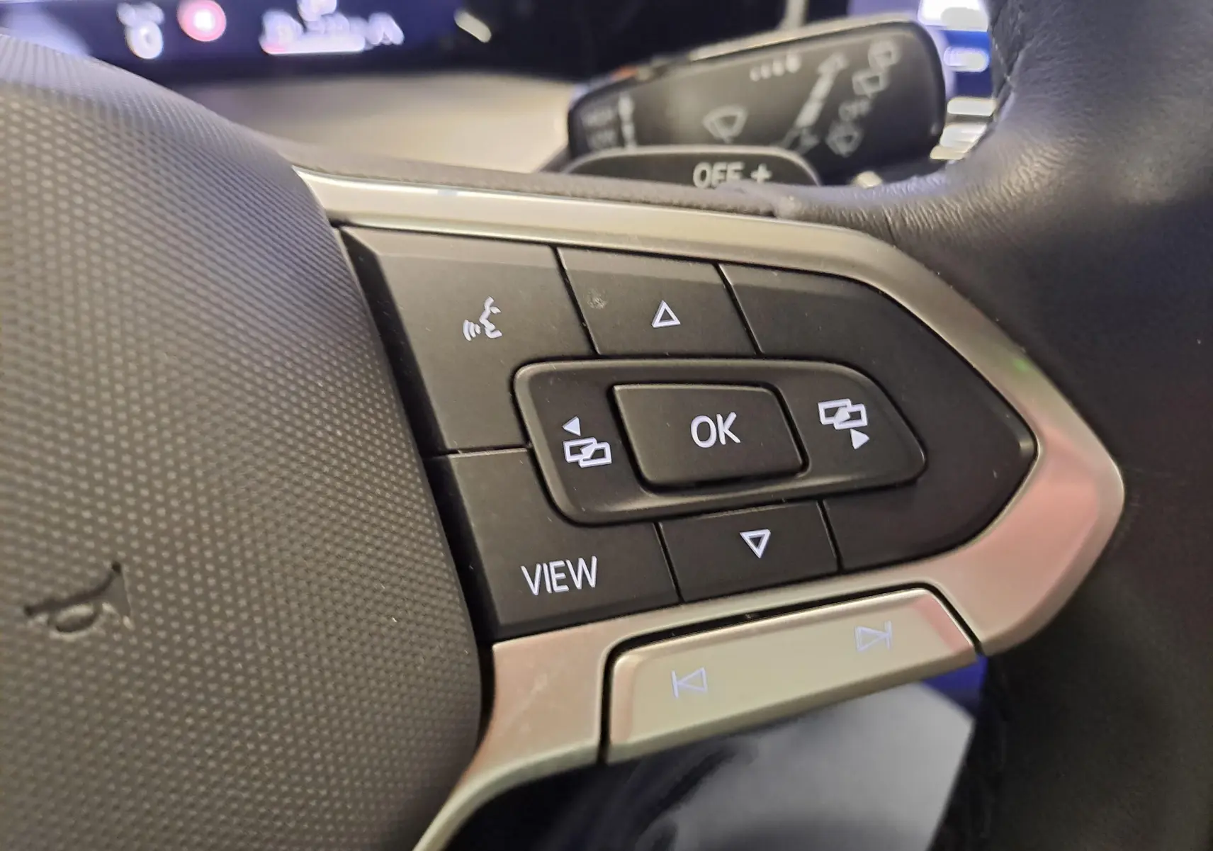 Gros plan sur les commandes multifonctions à droite du volant noir de la Volkswagen Golf 1.5 eTSI 150 DSG7 2024.