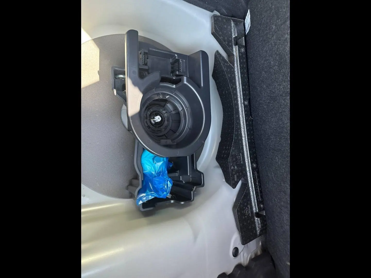 Détail du coffre de la Peugeot 208 2025 gris Selenium, montrant le rangement pour roue de secours et outils.