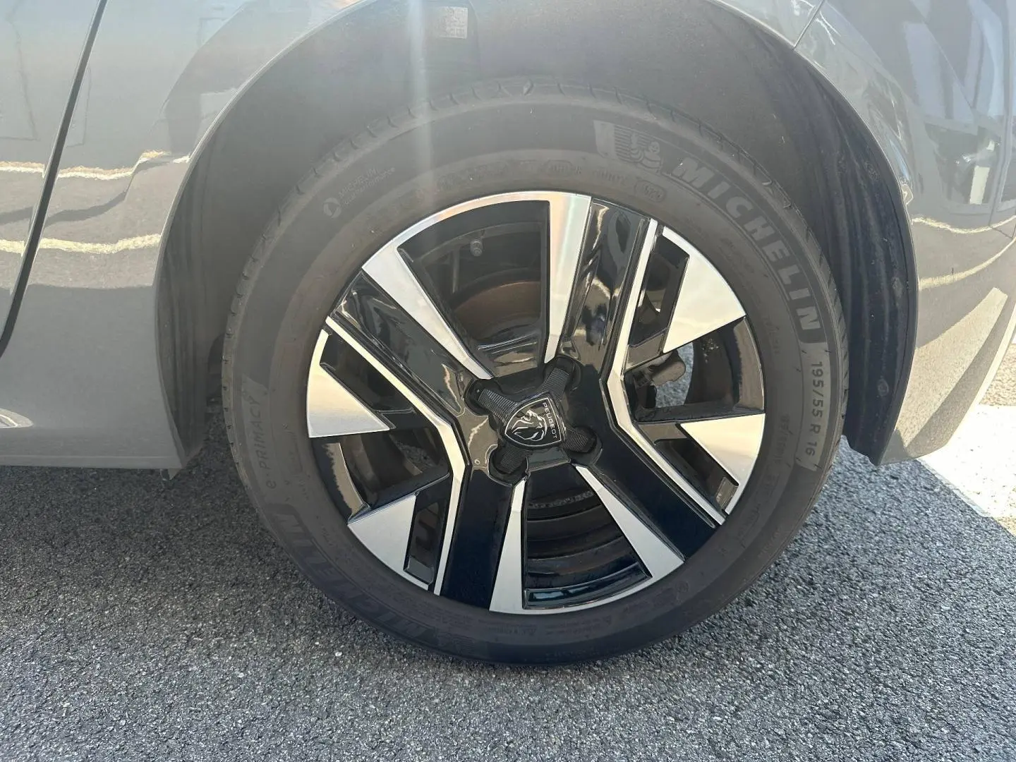 Gros plan sur la jante alu noire et argentée d'une Peugeot 208 gris Selenium, côté droit arrière.