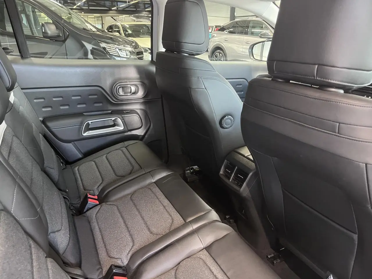 Vue intérieure arrière côté gauche du Citroën C5 Aircross 2025 avec sièges tissu et cuir gris et aérateurs centraux.