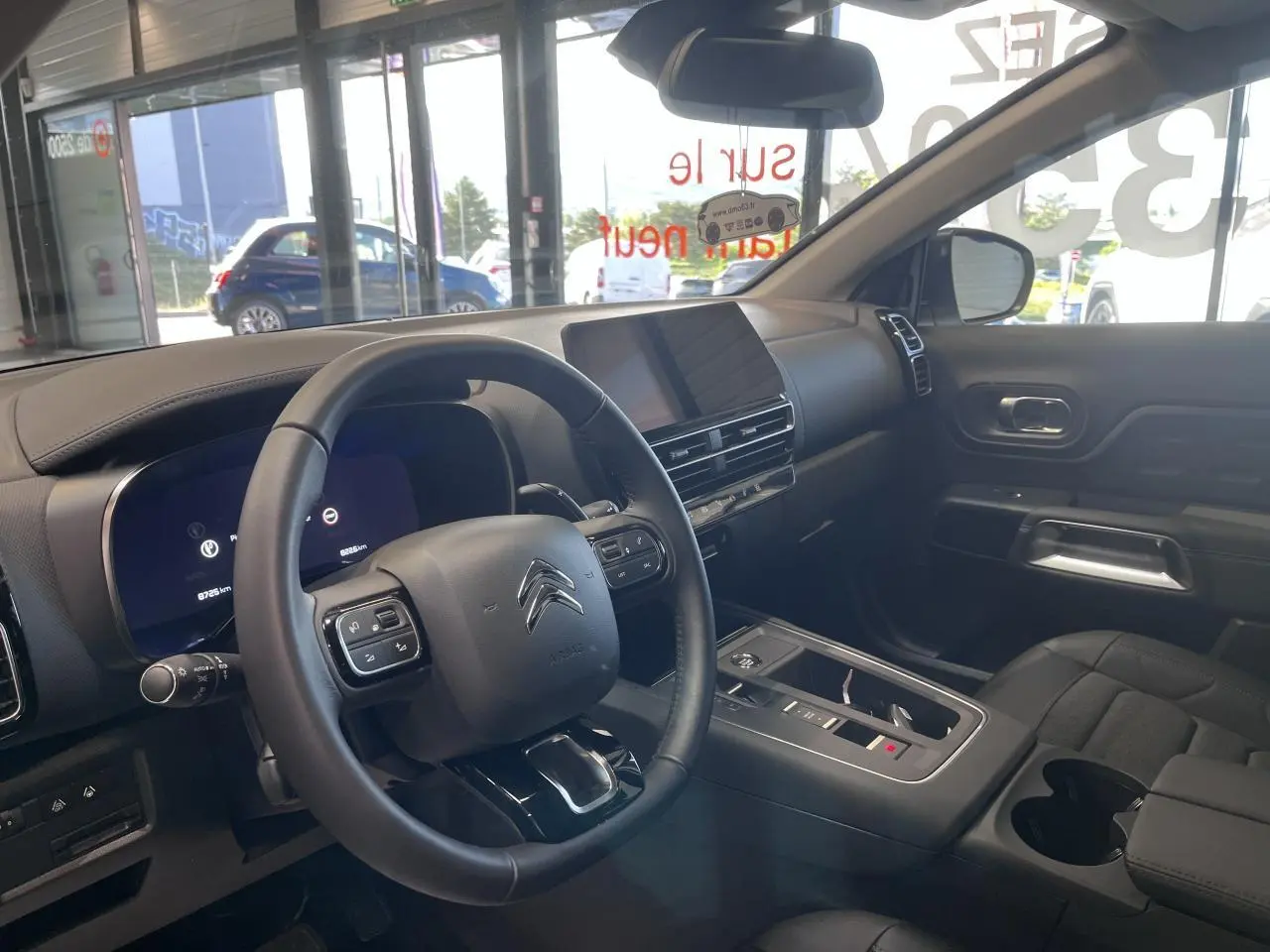 Intérieur du Citroën C5 Aircross 2025 en vue côté conducteur, volant cuir noir et écran tactile central.