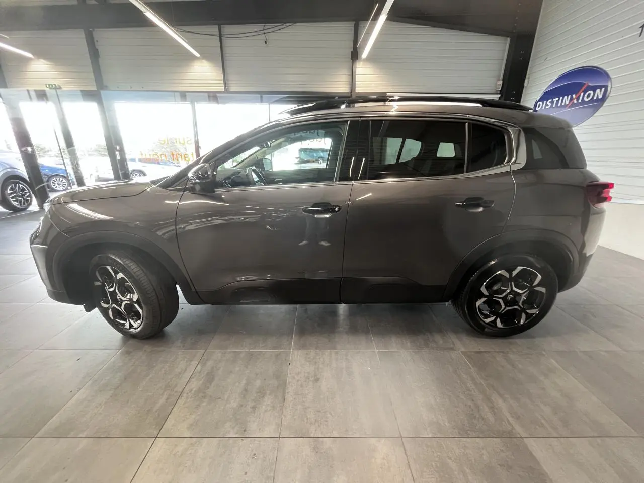 Vue de profil côté gauche d'un Citroën C5 Aircross gris platinium avec jantes alliage noires et toit noir brillant.