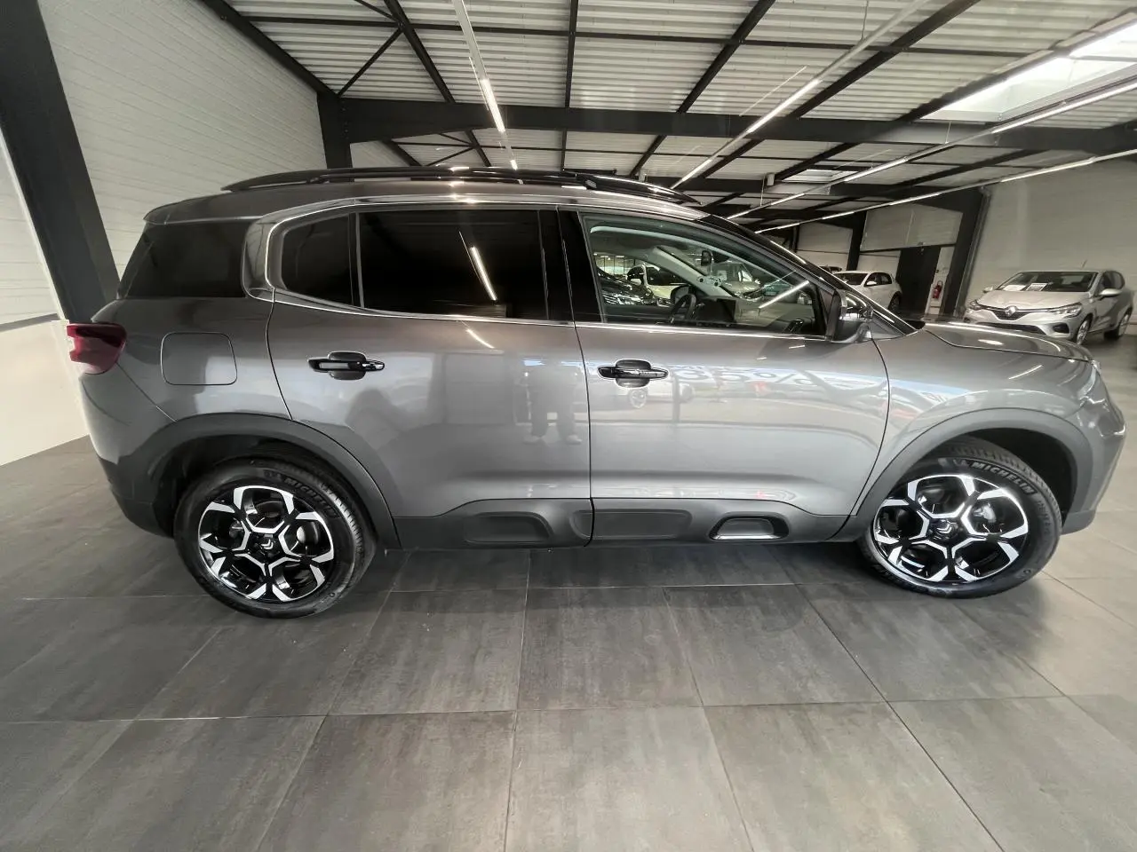 Vue de profil côté gauche d'un Citroën C5 Aircross gris platinium avec jantes alliage bi-ton et vitres surteintées.