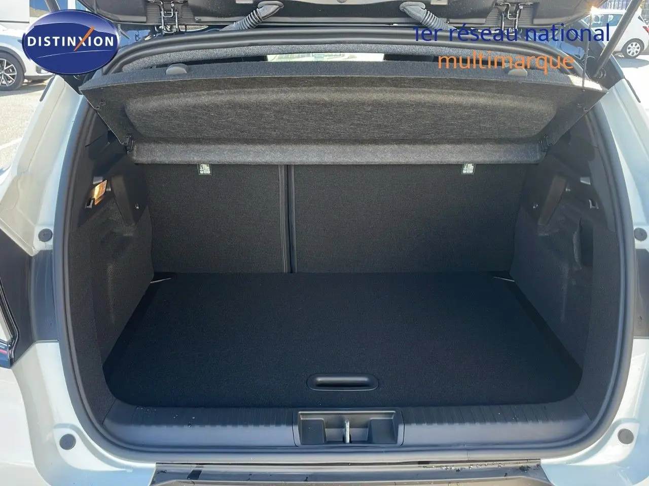 Coffre ouvert vu de l'arrière d'un Renault Captur E-Tech hybride blanc nacré avec toit noir, intérieur de coffre noir.