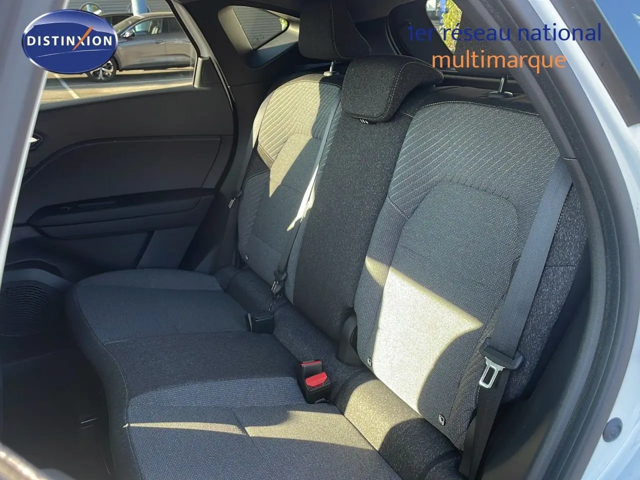 Vue intérieure sur la banquette arrière grise du Renault Captur blanc nacré avec ceinture de sécurité et porte ouvert côté droit.
