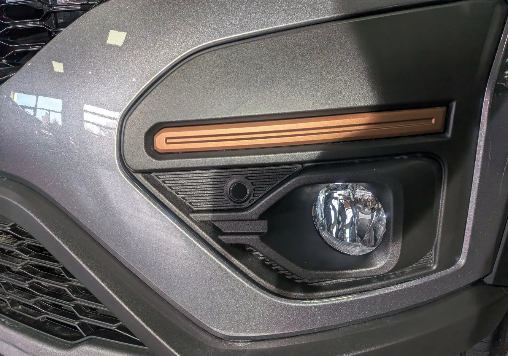 Gros plan sur le feu antibrouillard droit de la Dacia Sandero Stepway 2025 gris schiste avec insert décoratif cuivre.
