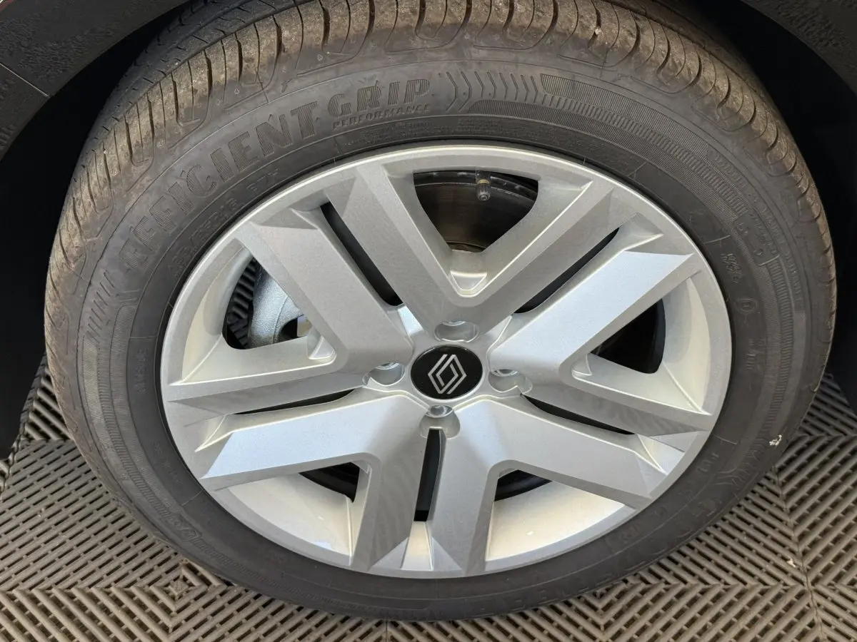 Gros plan sur la jante alliage argentée avec logo Renault au centre d'une Renault Clio noire 2025.