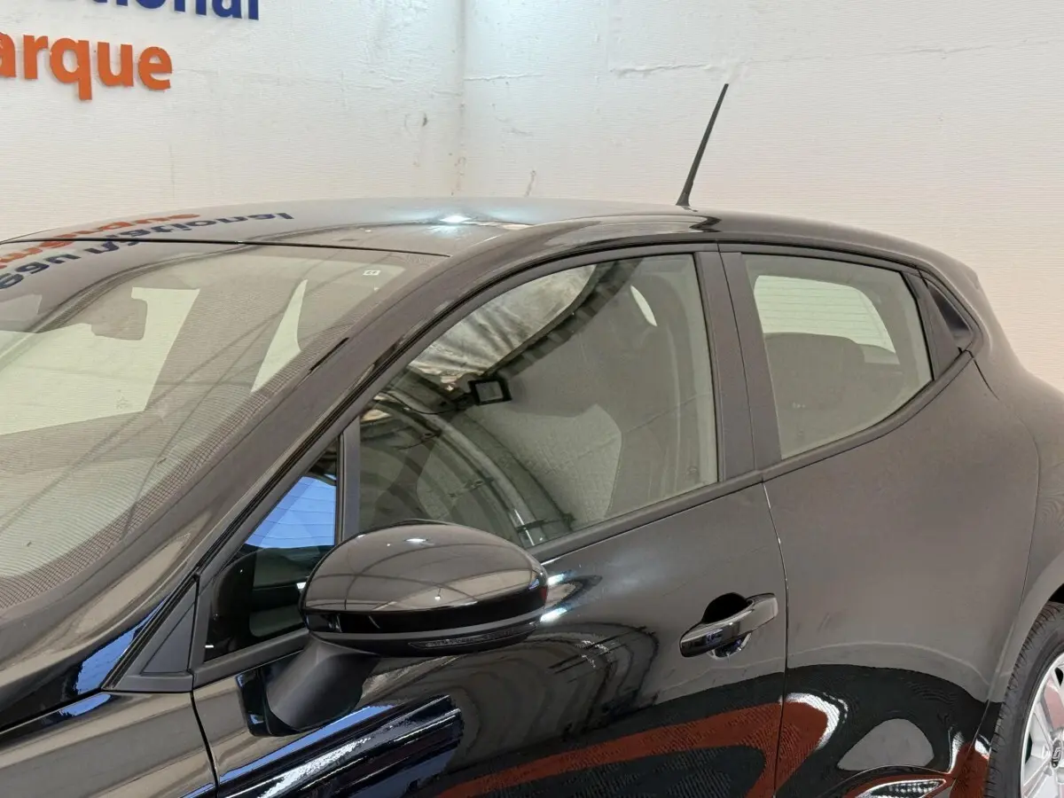 Vue latérale côté gauche d'une Renault Clio noire 2025 avec rétroviseur ton caisse et poignées de porte visibles.