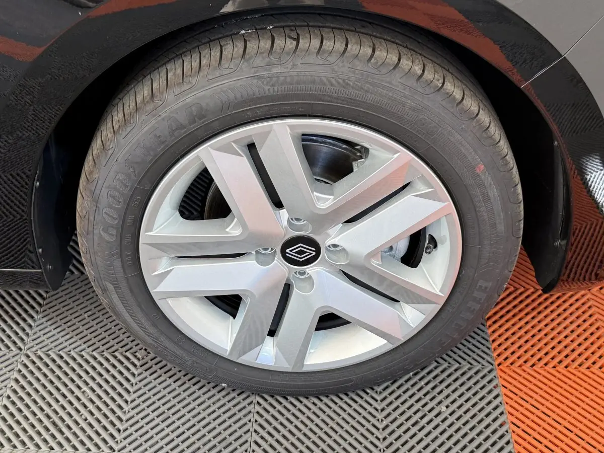 Gros plan sur la roue avant droite d'une Renault Clio noire 2025 avec jante alliage et logo central Renault.