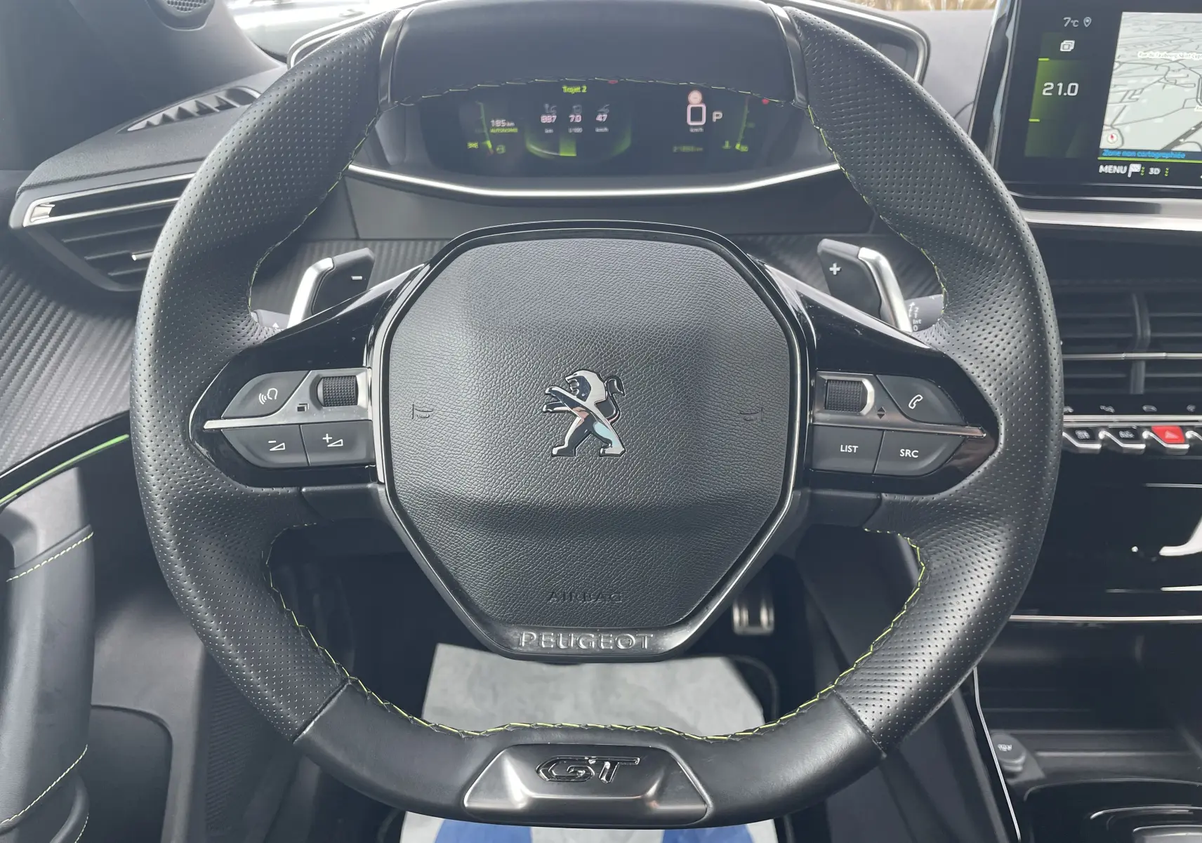 Vue rapprochée du volant cuir perforé noir avec surpiqûres vertes et logo GT du Peugeot 2008 gris Artense 2022.