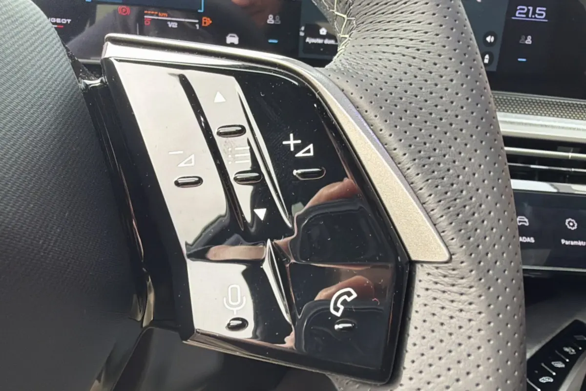 Gros plan sur le volant cuir perforé du Peugeot 3008 Hybrid 145 GT avec commandes multifonctions noires brillantes.