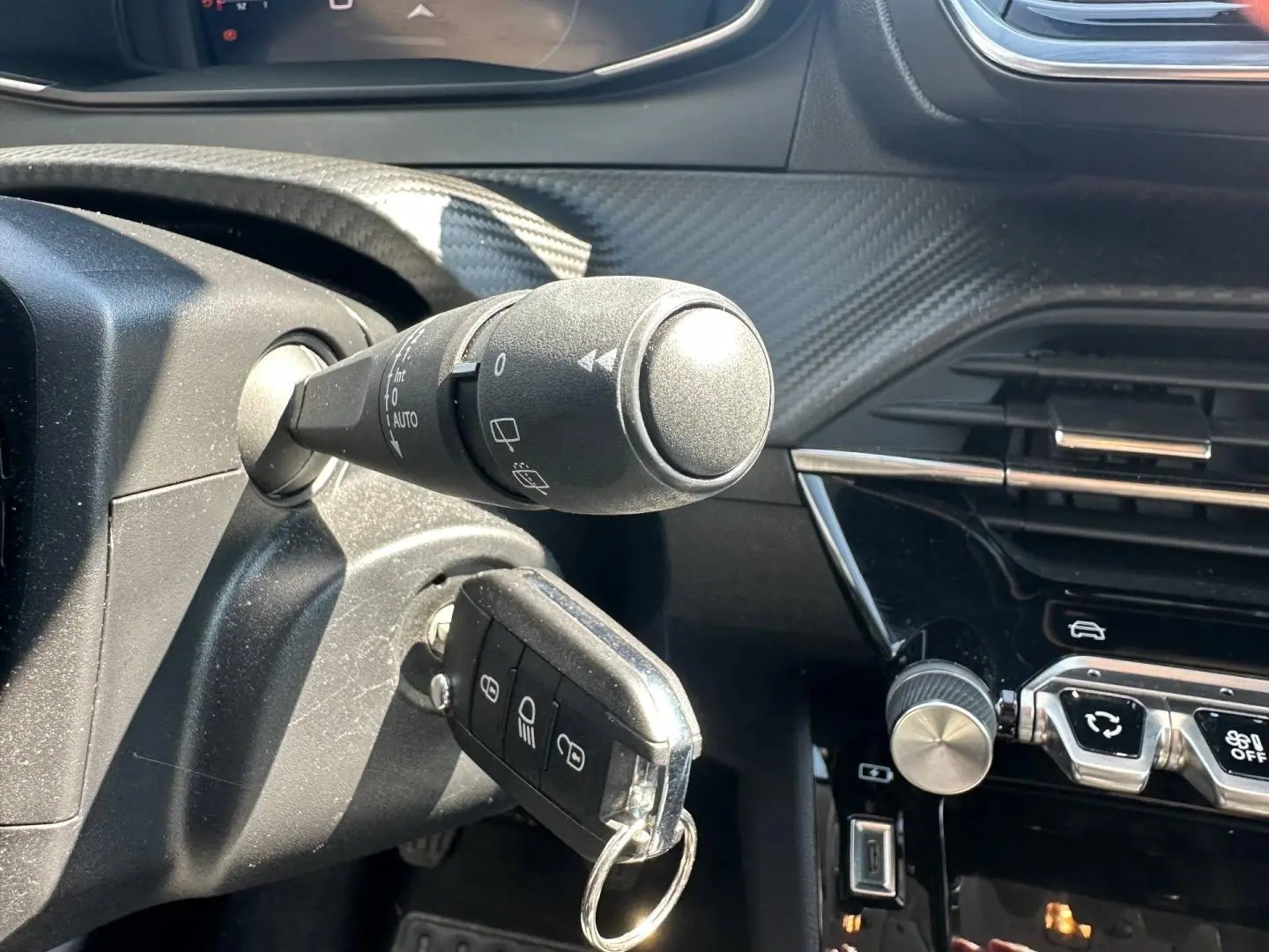 Gros plan sur le contacteur avec clé insérée et partie gauche du tableau de bord noir brillant de la Peugeot 208 gris Selenium.