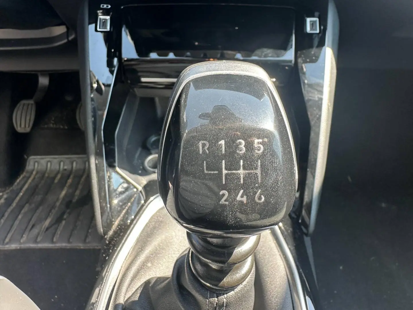 Gros plan sur le levier de vitesses manuel noir de la Peugeot 208 1.2 100ch Allure, entouré de la console centrale noire.