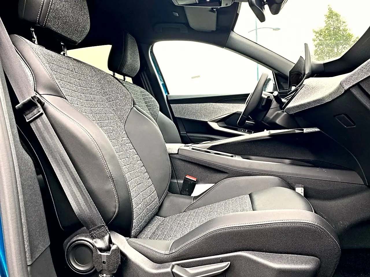 Vue intérieure côté conducteur de la Peugeot 3008 2025 bleu, sièges tissu et cuir avec console centrale moderne.