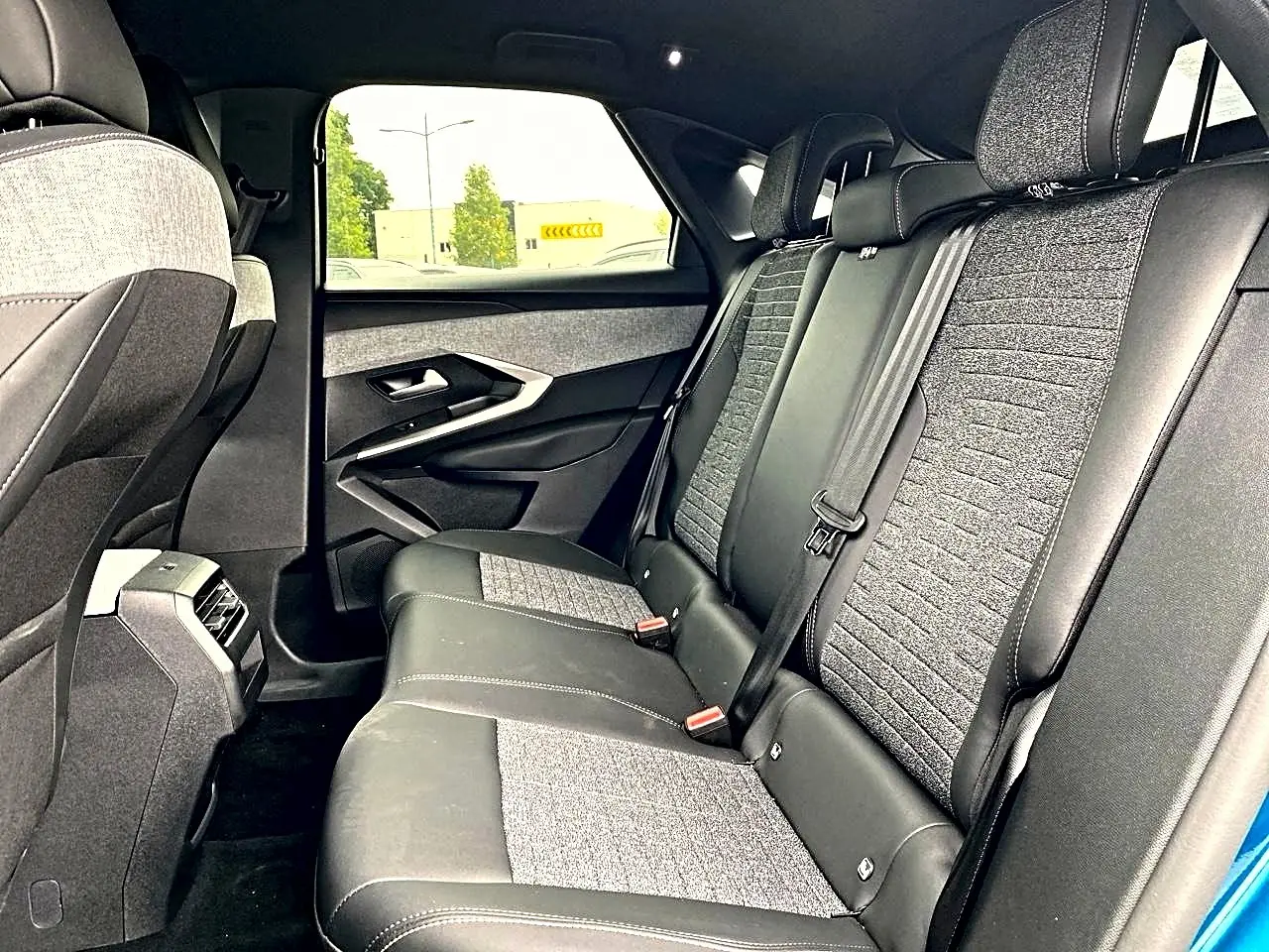 Vue intérieure côté droit des sièges arrière gris et noir du Peugeot 3008 1.2 hybrid 145 allure e-dcs6 bleu 2025.
