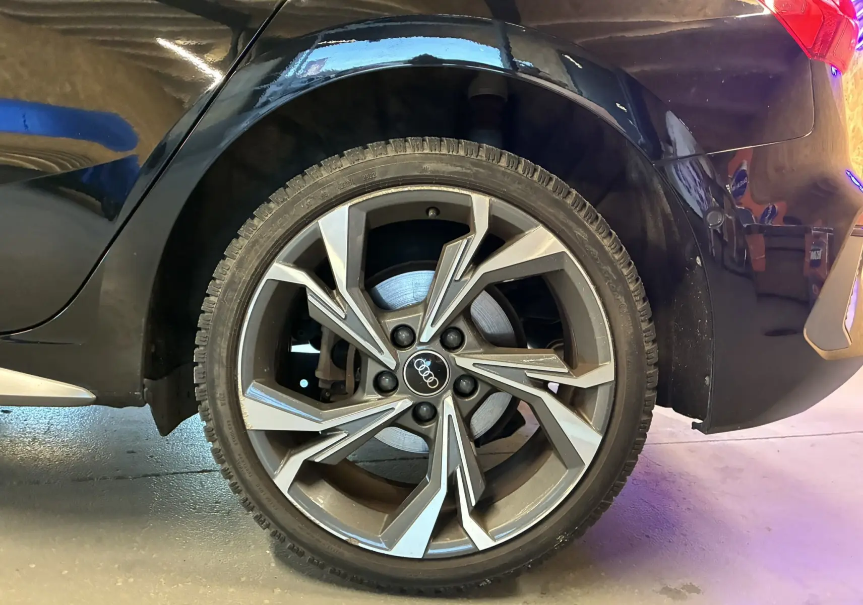 Vue rapprochée du côté arrière droit d'une Audi A3 Sportback noire 2022, mettant en valeur l'aile et le feu arrière.