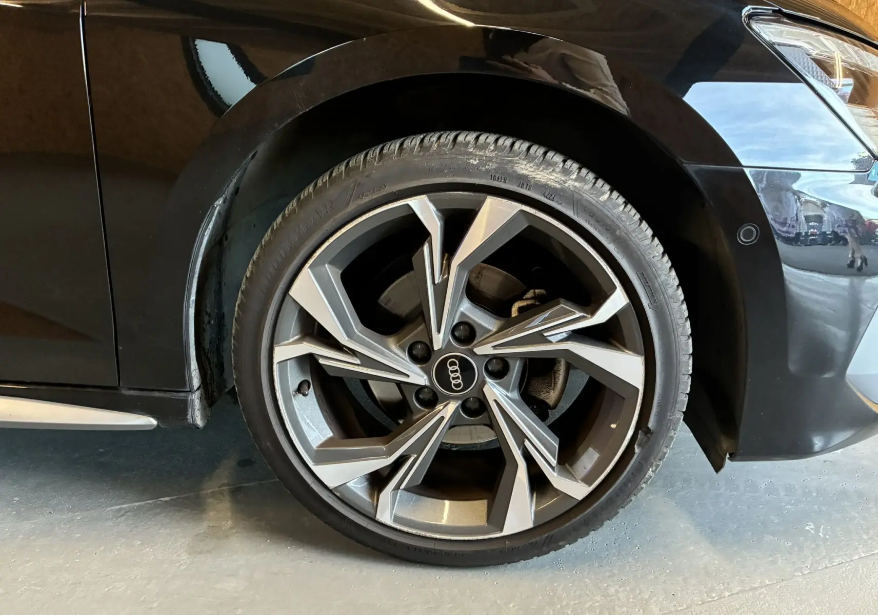 Gros plan sur la roue avant droite noire d'une Audi A3 Sportback 2022 avec jante alliage et capteur de stationnement.