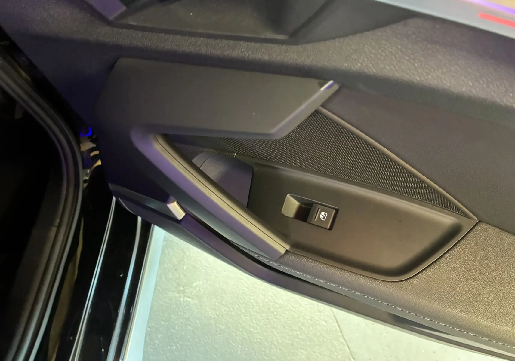 Gros plan sur la poignée intérieure et le bouton de lève-vitre côté gauche d'une Audi A3 Sportback noire de 2022.