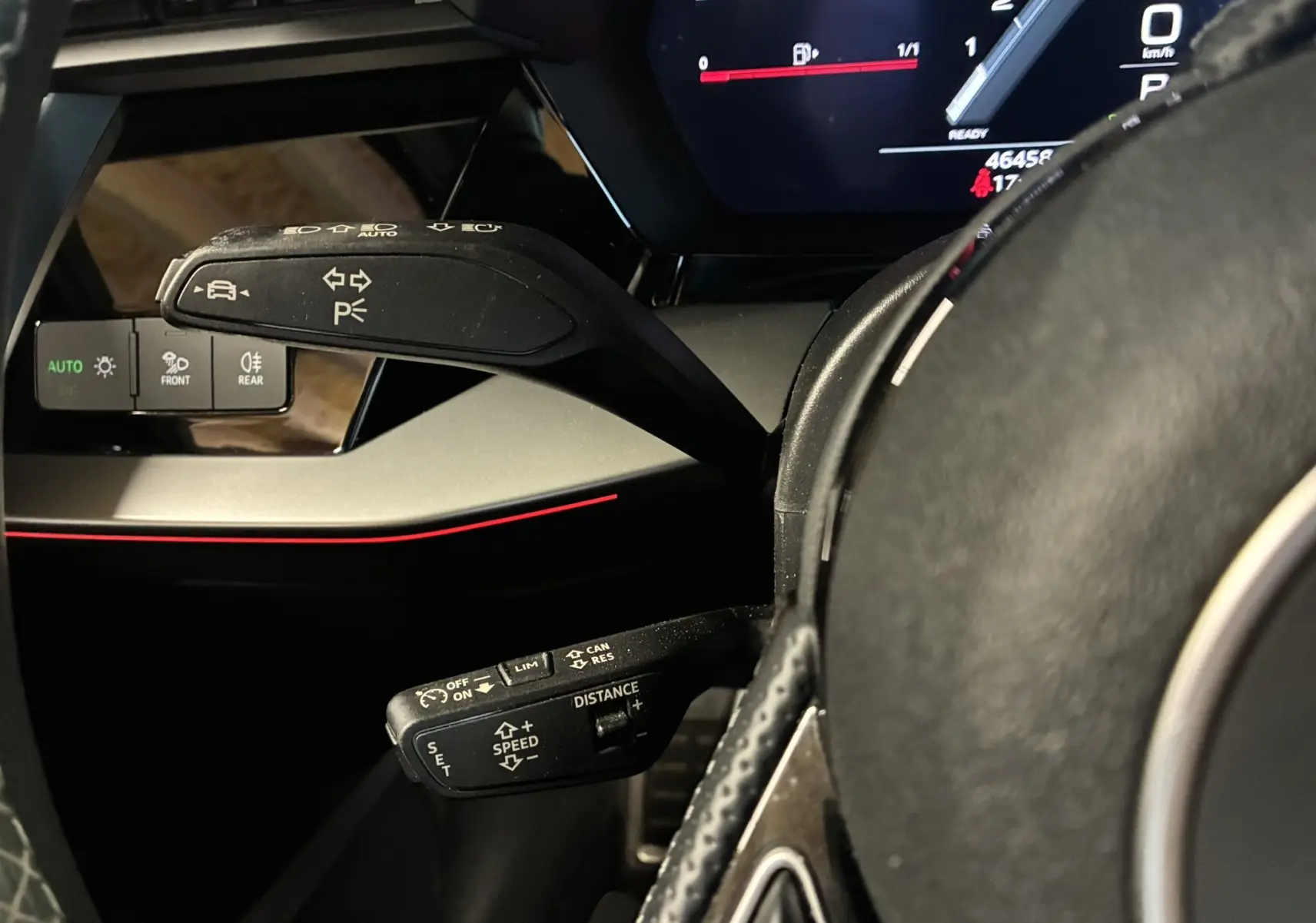 Gros plan sur les commandes au volant noir d'une Audi A3 Sportback 2022, avec affichage digital et éclairage d'ambiance rouge.