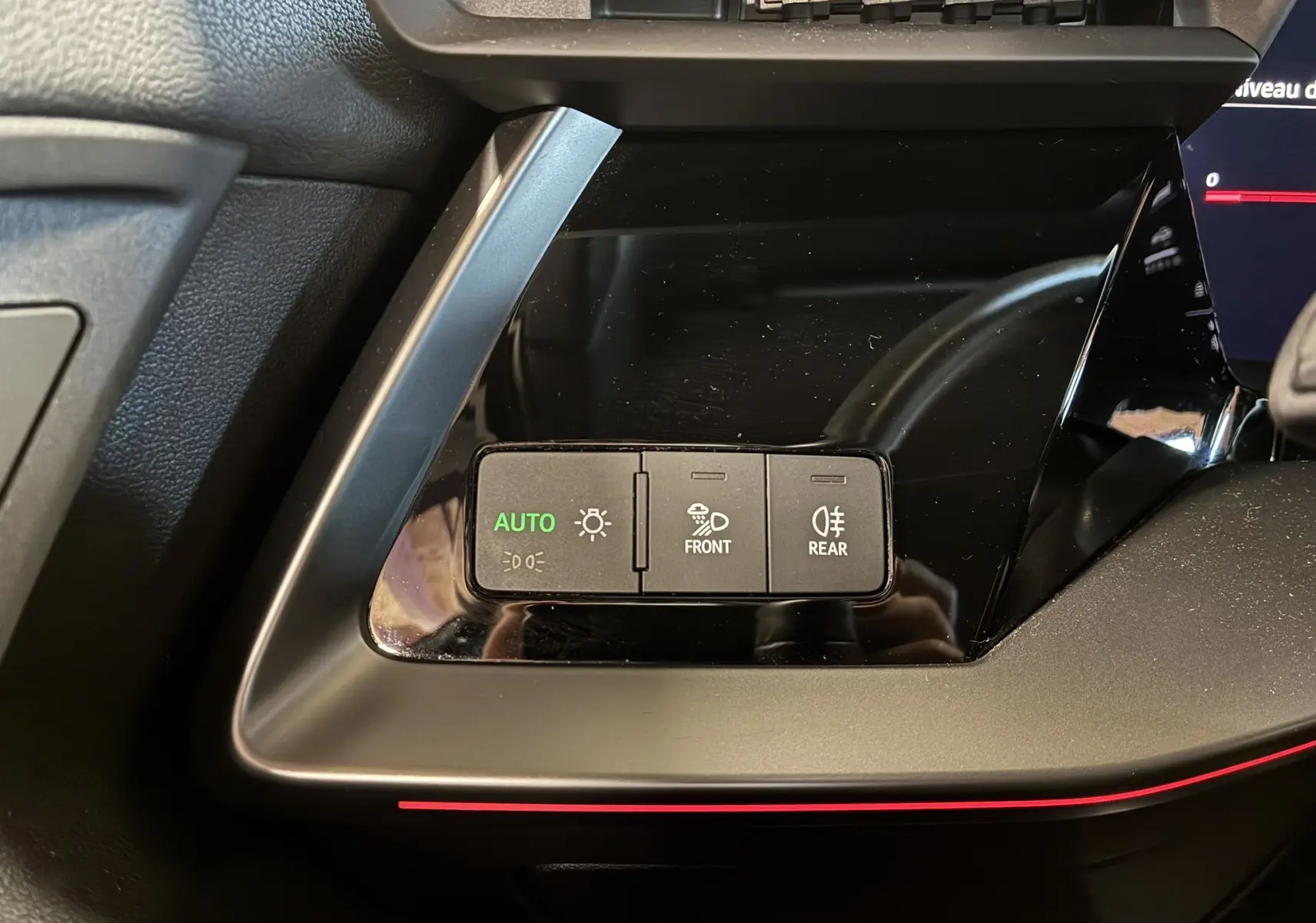 Gros plan sur les commandes d'éclairage avec mode auto activé dans l'habitacle noir d'une Audi A3 Sportback 2022.