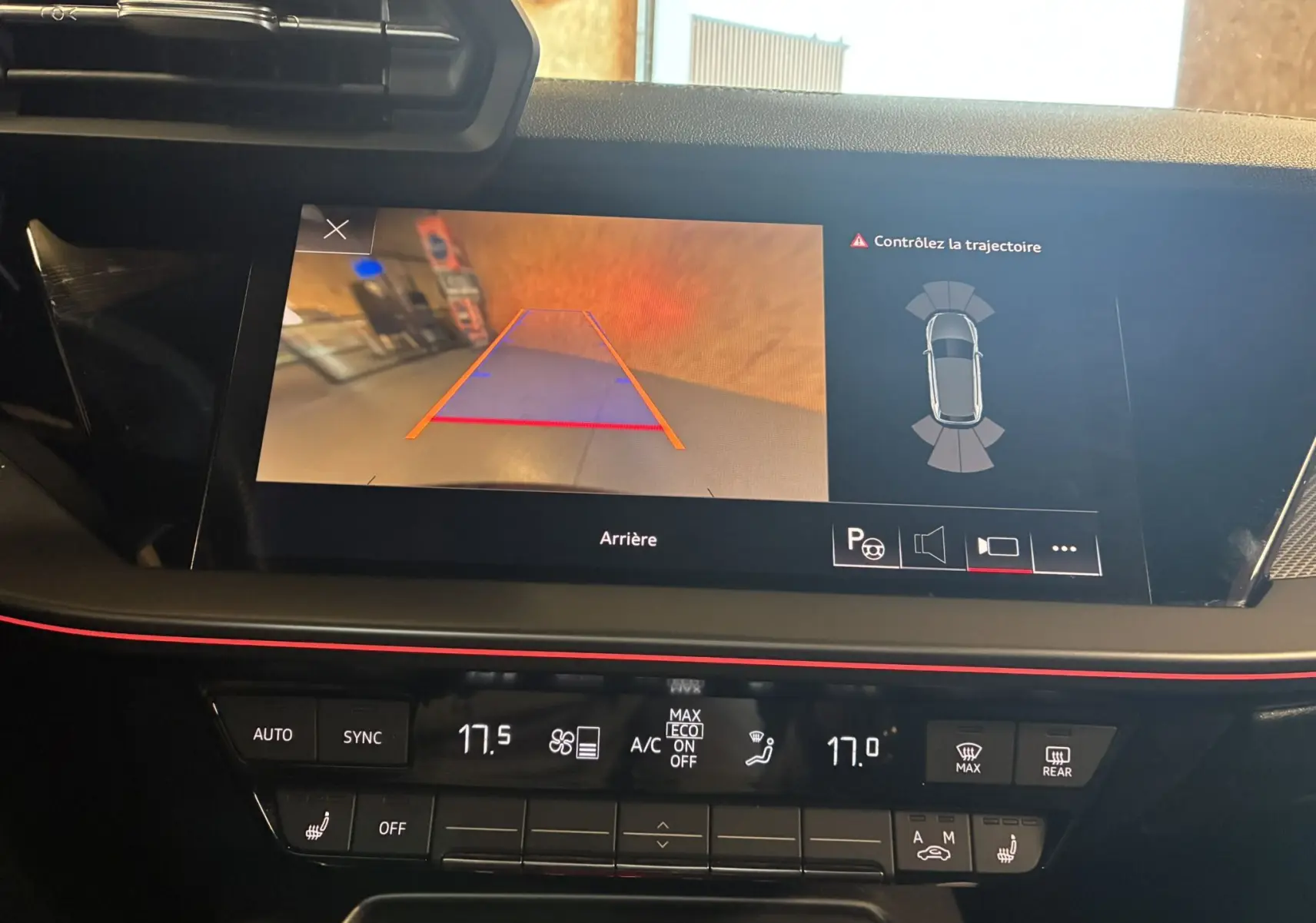 Vue intérieure du tableau de bord de l'Audi A3 Sportback 2022 avec écran de caméra de recul et commandes de climatisation noires.