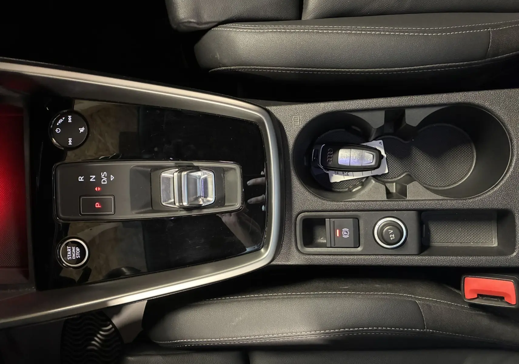 Vue plongeante sur la console centrale noire de l'Audi A3 Sportback avec levier de vitesse automatique et clé Audi dans porte-gobelet.