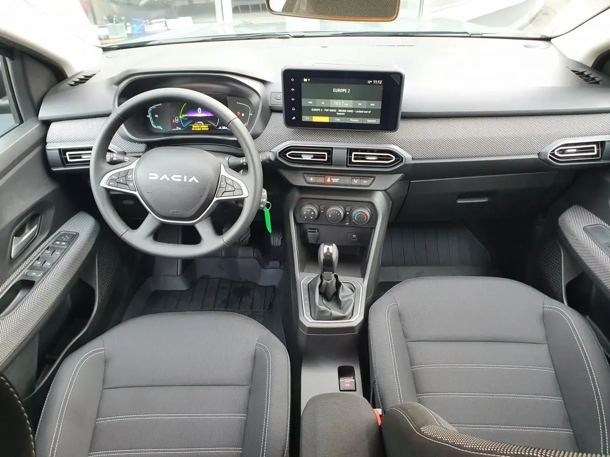 Vue intérieure frontale du tableau de bord et volant du Dacia Jogger 2024, avec écran tactile et sellerie noire.