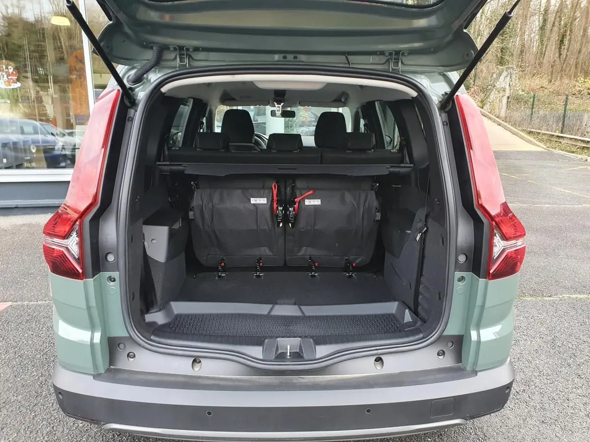 Vue arrière ouverte du Dacia Jogger 2024 en Licken Kaki, montrant le coffre spacieux avec banquette rabattue et feux arrière rouges.