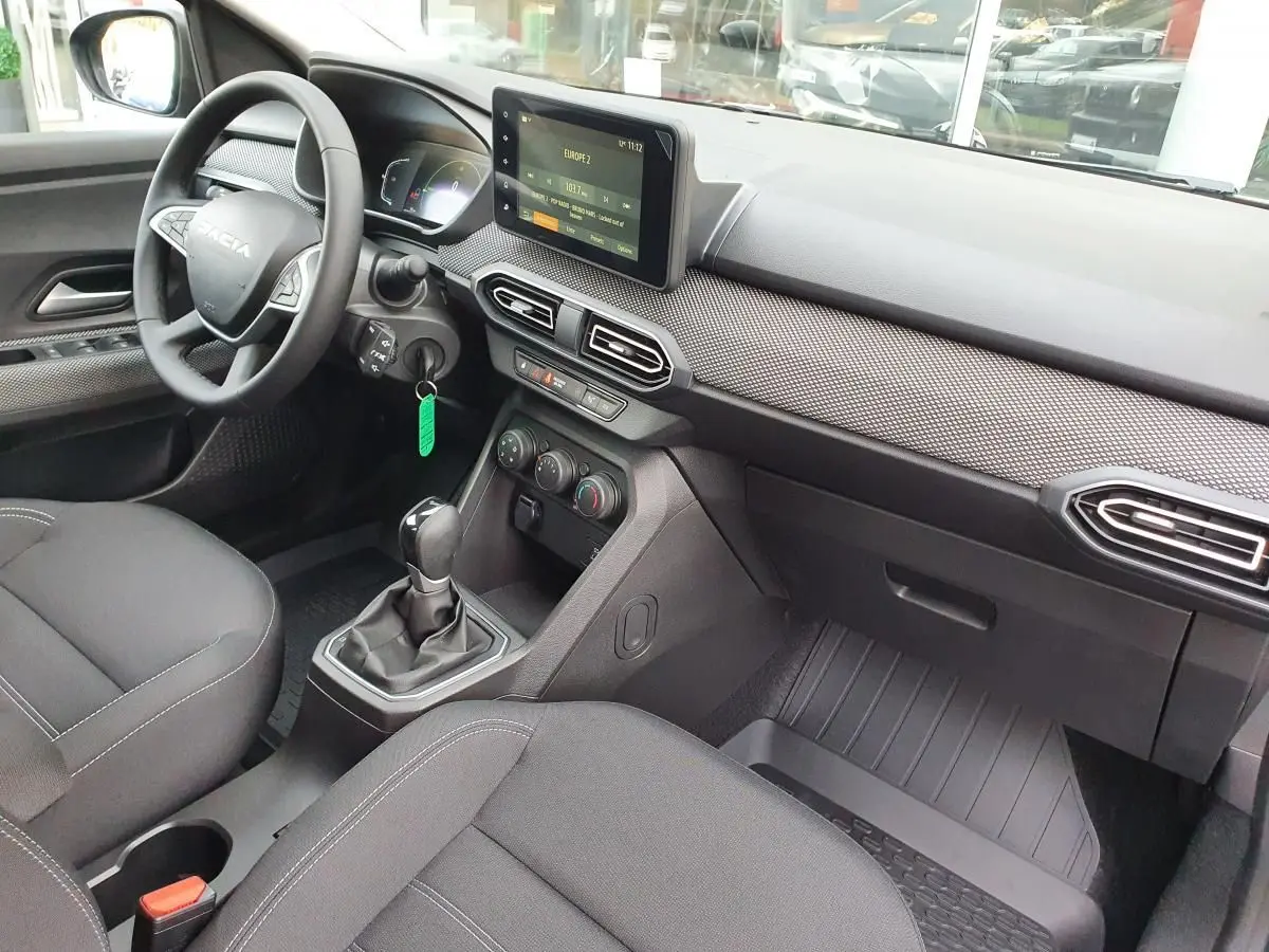 Vue intérieure côté conducteur du Dacia Jogger 2024, tableau de bord avec écran tactile et volant multifonction noir.