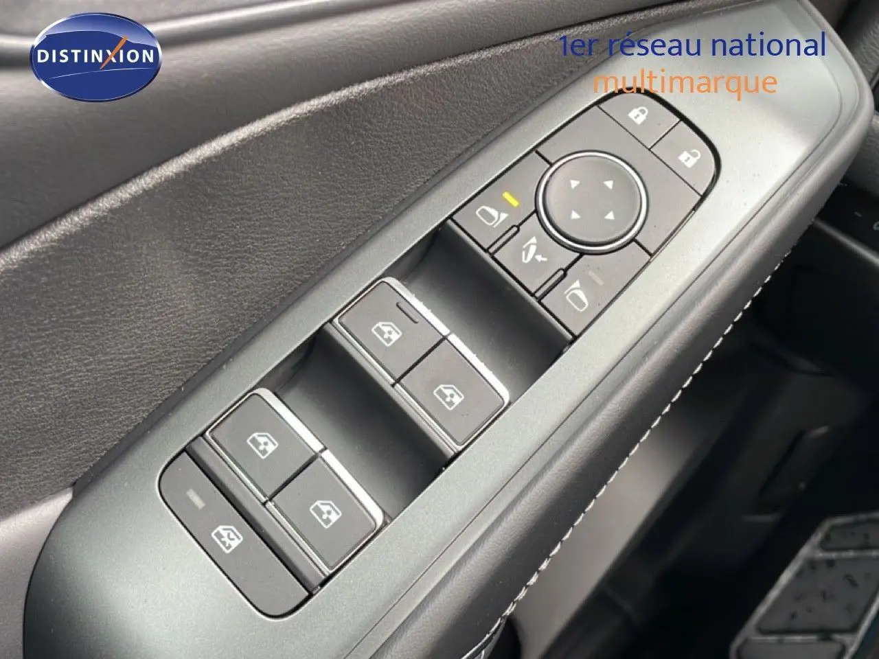 Gros plan sur les commandes de lève-vitres et rétroviseurs côté conducteur du Nissan Qashqai gris, avec surpiqûres blanches visibles.