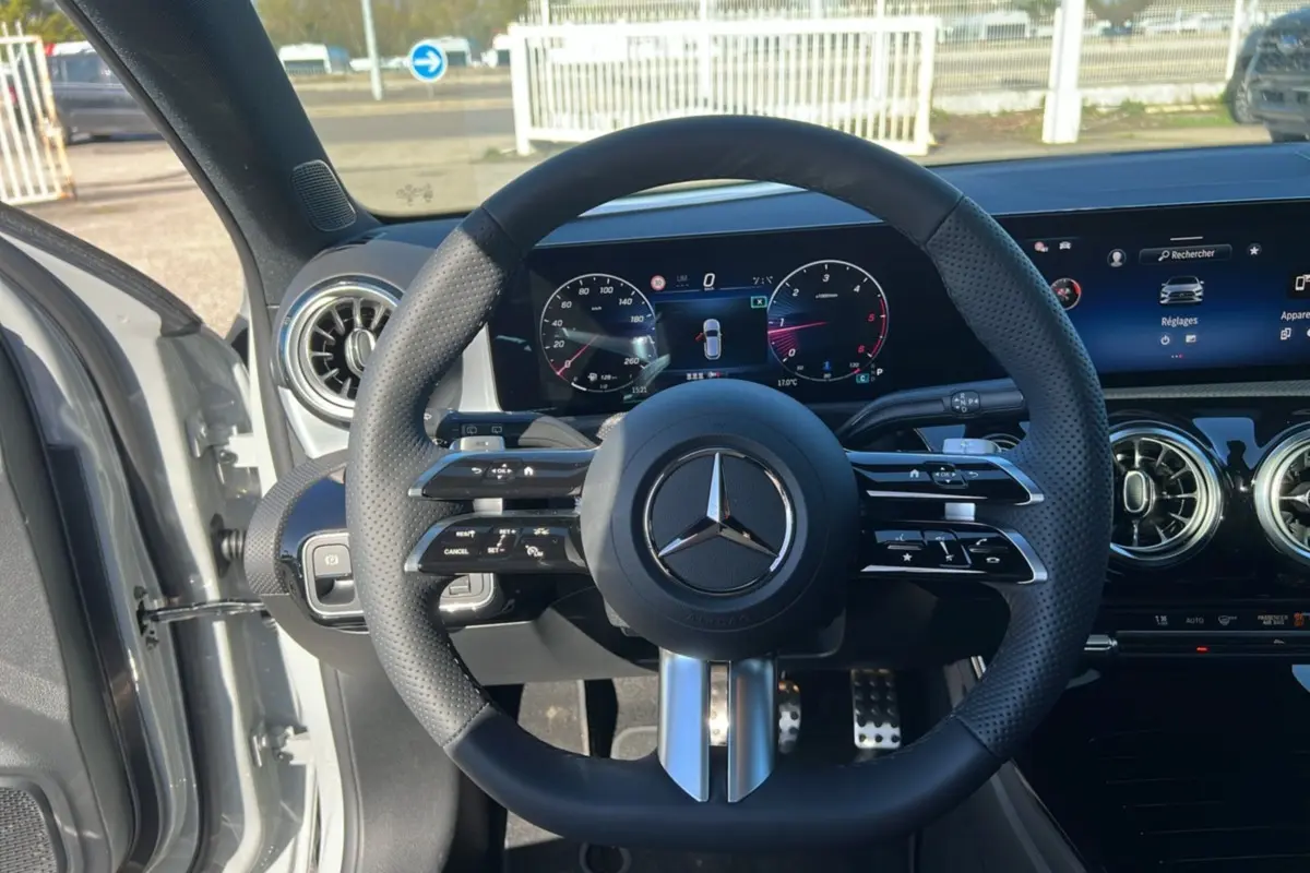 Vue intérieure centrée sur le volant cuir multifonctions de la Mercedes Classe A 200D, avec tableau de bord digital et aérateurs ronds.