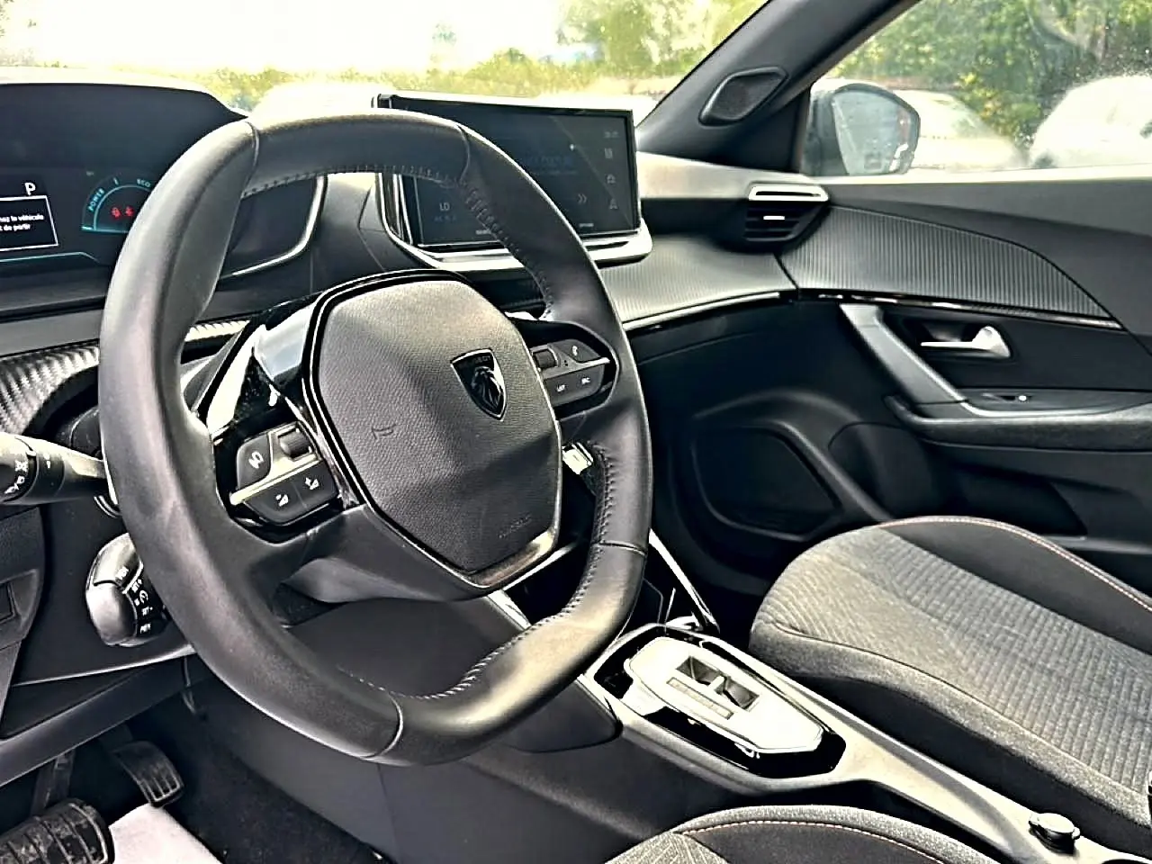 Intérieur du Peugeot 2008 hybride 2025, vue côté conducteur, volant multifonction et tableau de bord numérique.