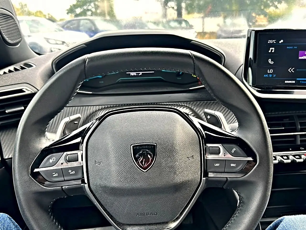 Vue centrée sur le volant cuir noir du Peugeot 2008 gris, avec commandes intégrées et tableau de bord numérique.