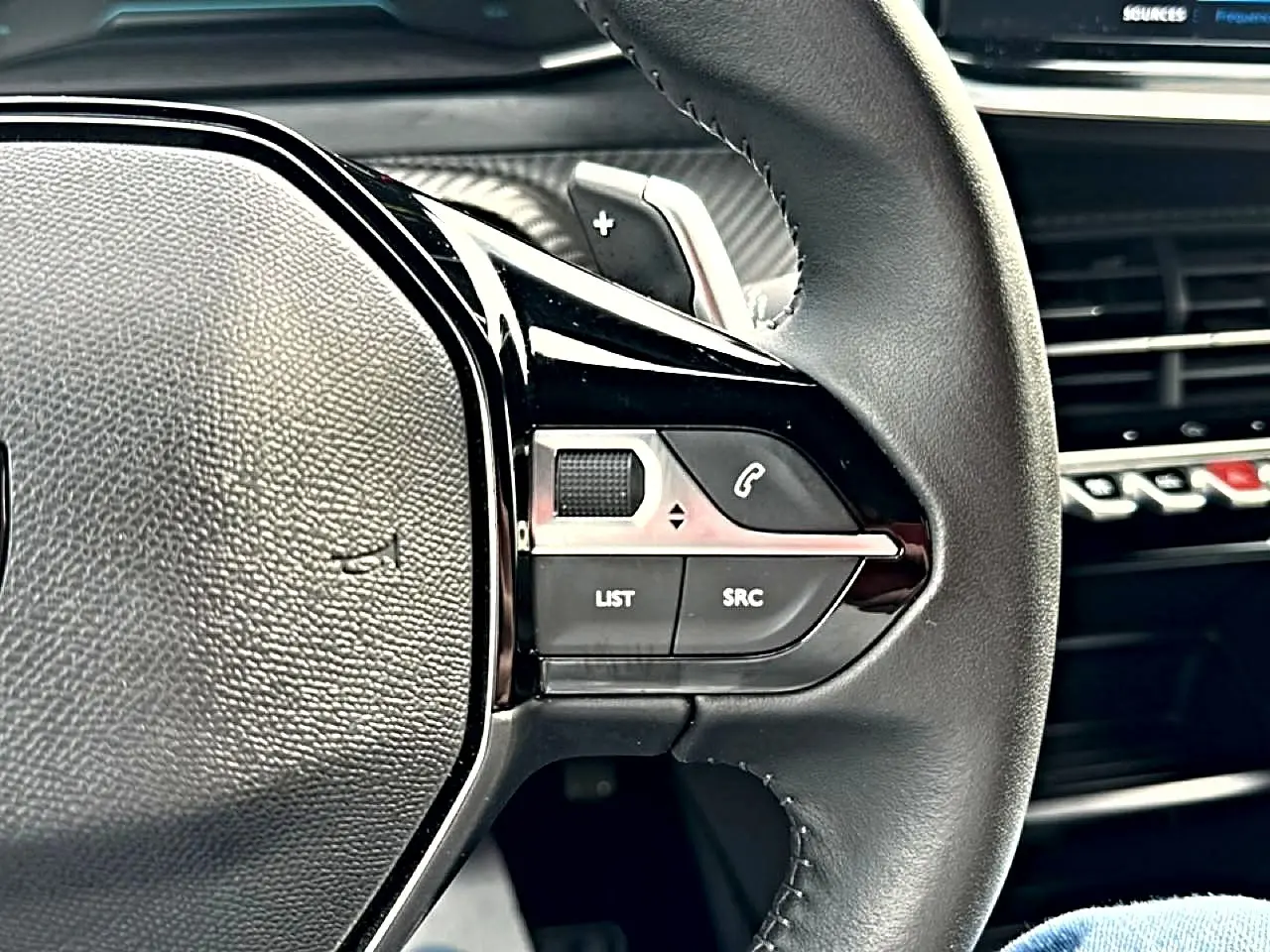 Gros plan sur la partie droite du volant noir du Peugeot 2008 gris, avec commandes audio et téléphone intégrées.